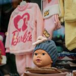 A colorful children's clothing store display featuring a doll head wearing a beanie.