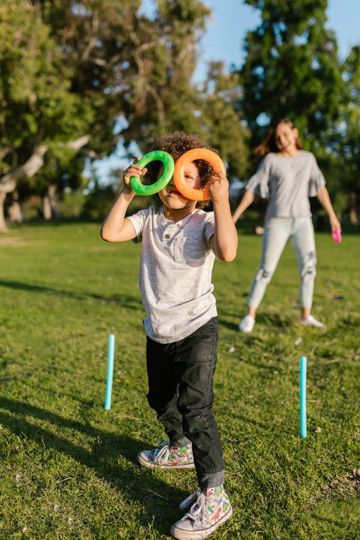 A cheerful child playing a fun game with colorful rings in a sunny park.